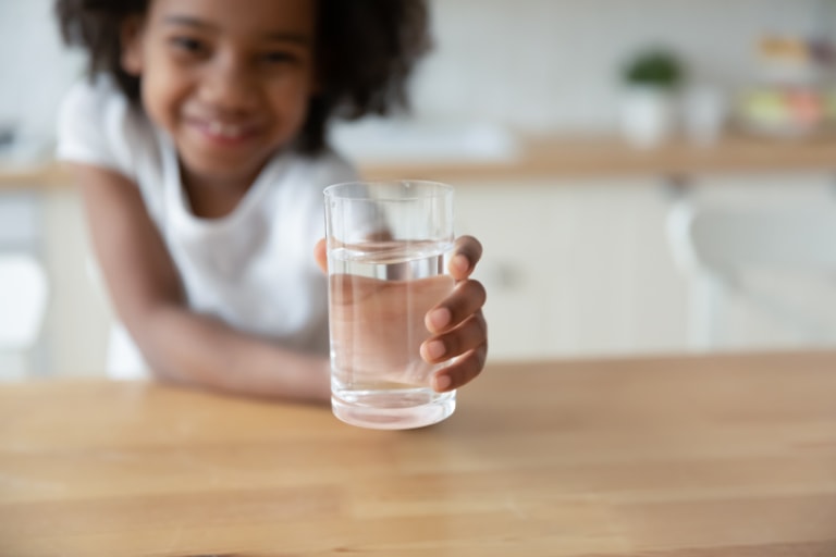 girl holding out water glass